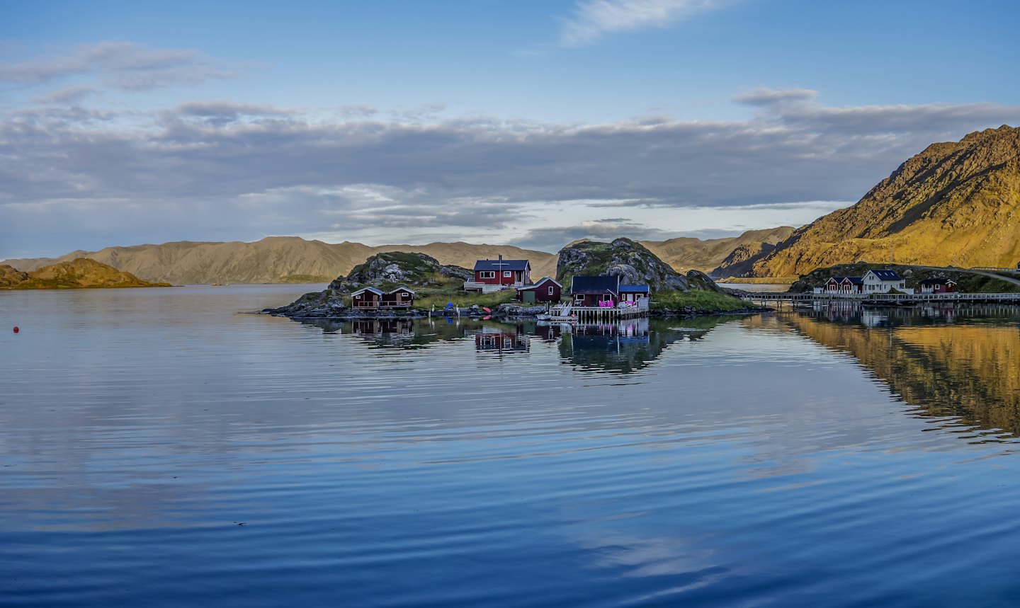 Røde og hvite hus på øyer i en rolig fjord.